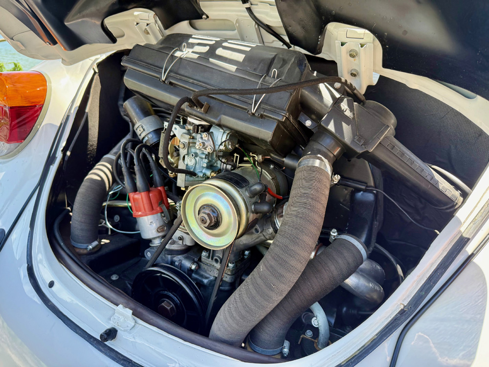 Clean air cooled Volkswagen Super Beetle engine showing carburettor, hoses and red distributor cap