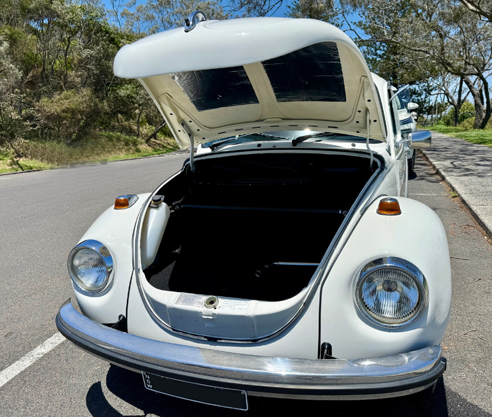 Open front trunk of a classic Volkswagen Super Beetle showing the empty storage compartment