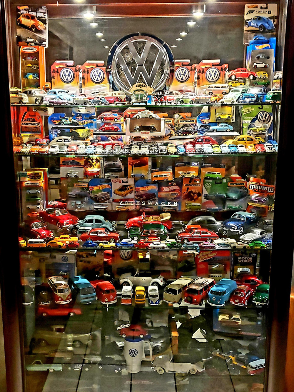 Glass cabinet filled with Volkswagen toy cars, vans and memorabilia in original packaging