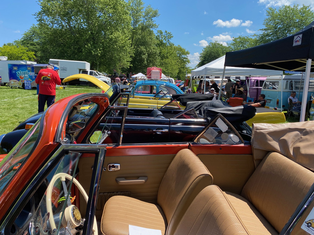 Red convertible Volkswagen Beetle interior in foreground with show cars lined up behind