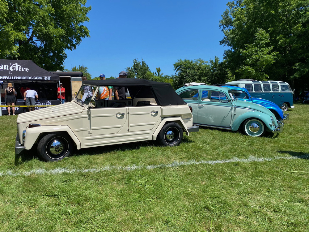 Cream VW Thing with Beetles and a Bus behind it at Germanaire on a sunny day