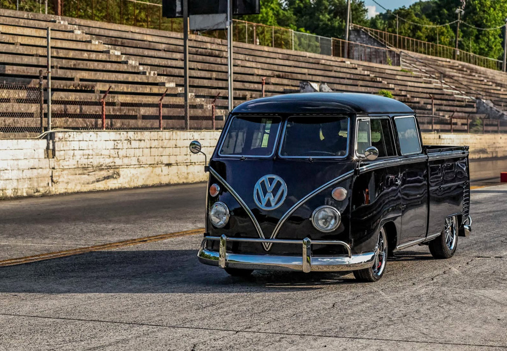 Classic black VW Type 2 Double Cab parked near empty concrete bleachers