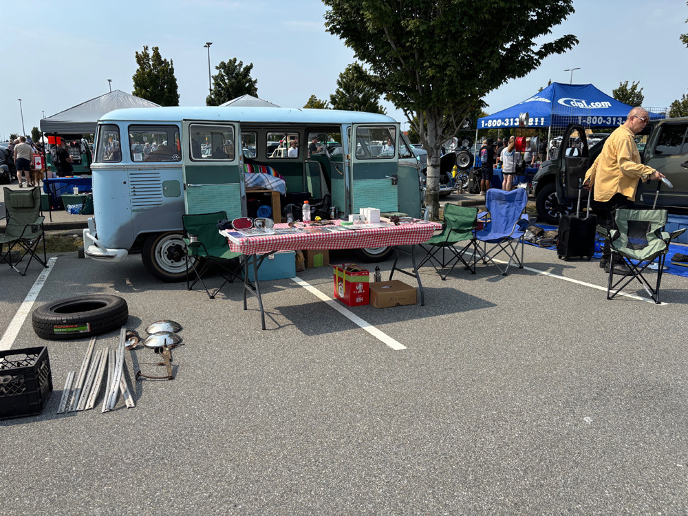 Vintage VW Bus set up for the swap meet with tables, parts and vendors in a busy parking lot