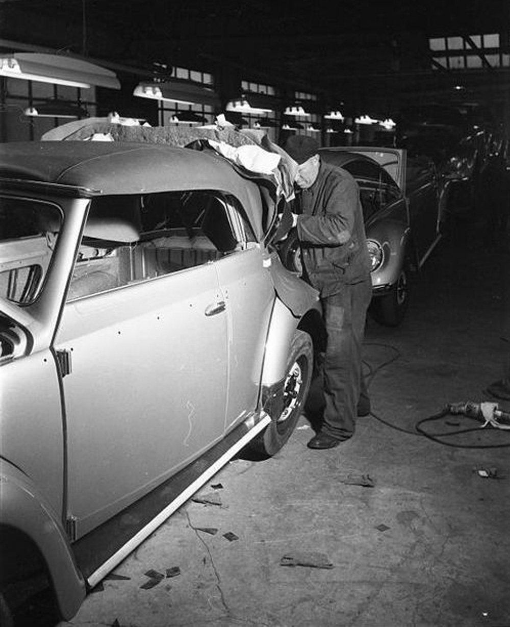 A worker at the Karmann factory is using his skills to perfectly install a convertible top