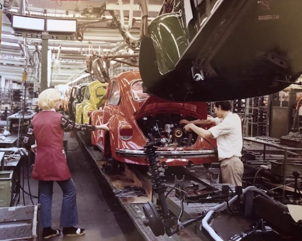 Two workers working together as the chassis and Super Beetle body come together in a process called the marriage